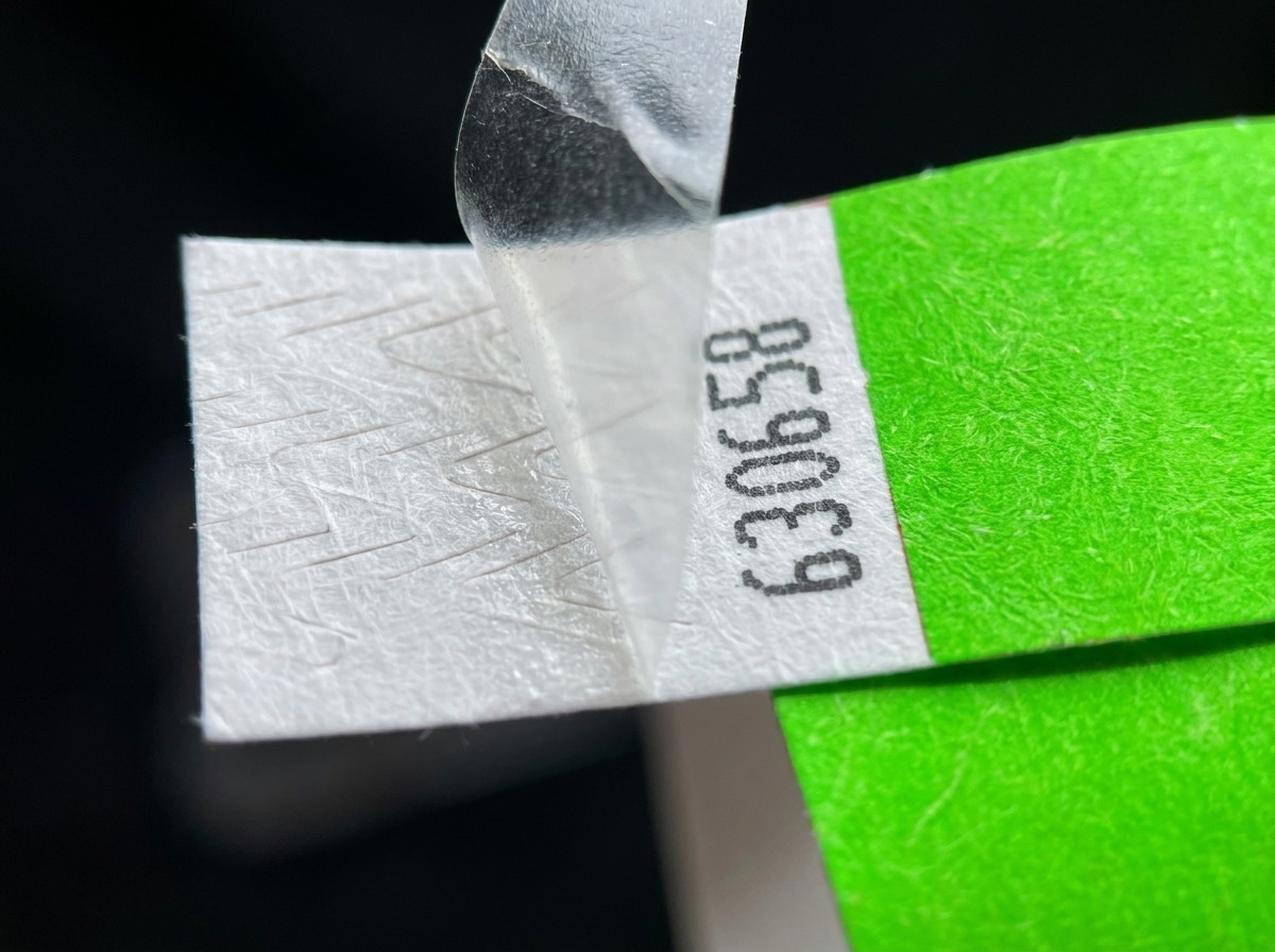 Gros plan sur la fermeture anti-transfert d'un bracelet identification, montrant le mécanisme de clip irréversible