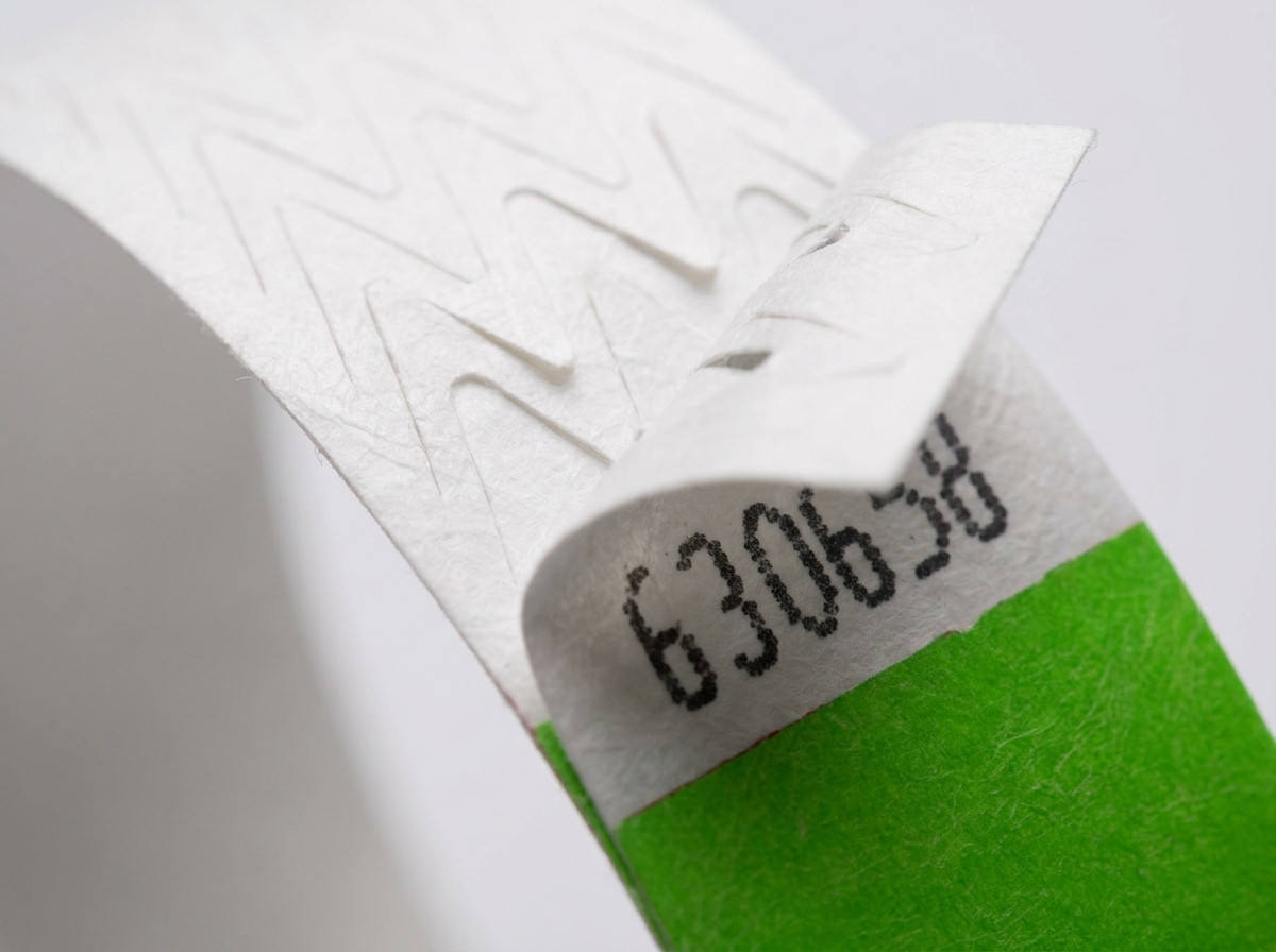 Gros plan sur la fermeture anti-transfert d'un bracelet Tyvek coloré lors d'un contrôle d'accès à un festival